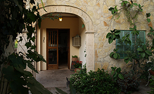 The stone arch and green shuttered entrance to Villa Ampurdán, framed by climbing vines